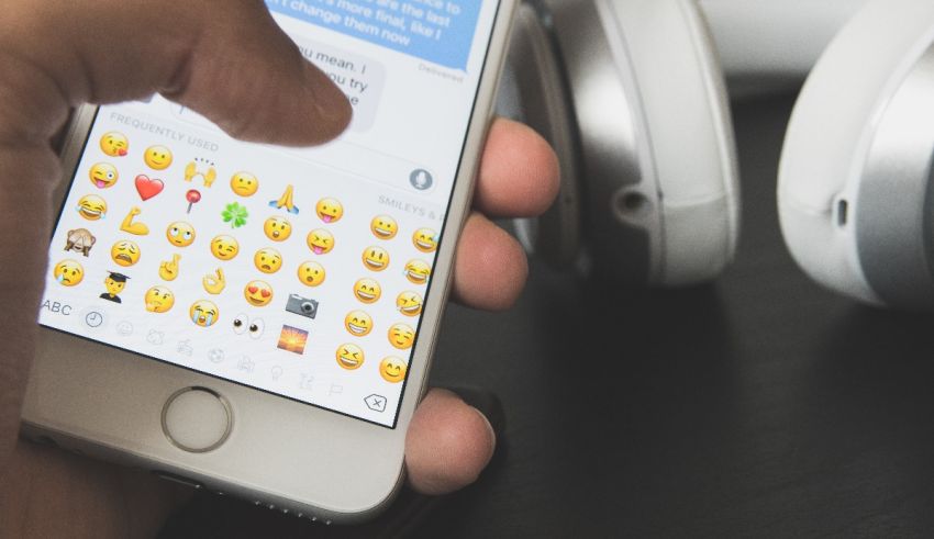 A person holding an iphone with emojis on it.