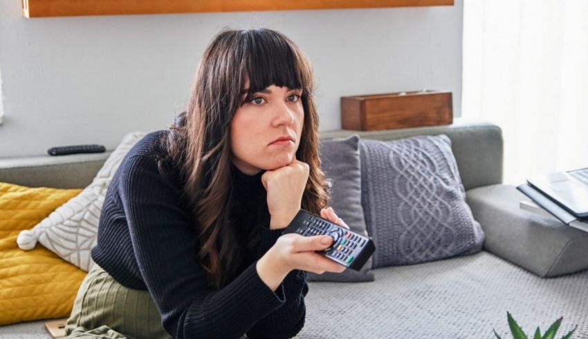 A woman sitting on the couch holding a remote control.
