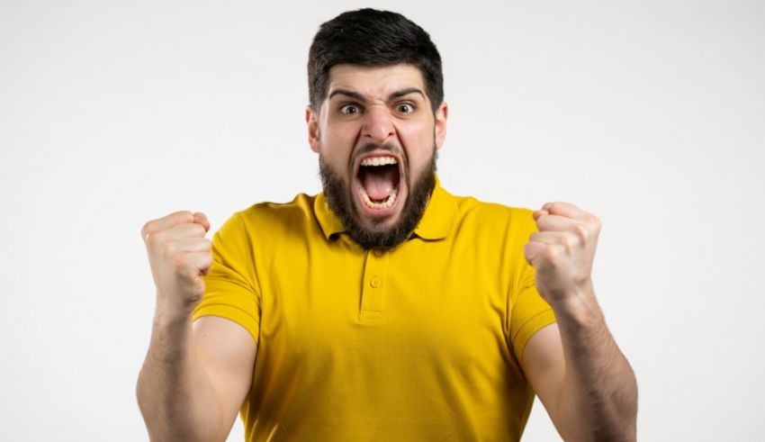 A man in a yellow shirt is screaming with his fists up.