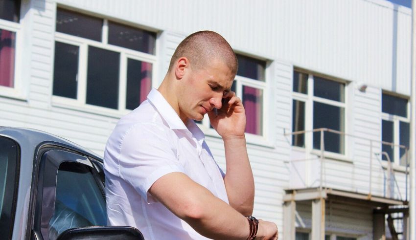 A man talking on a cell phone near a car.