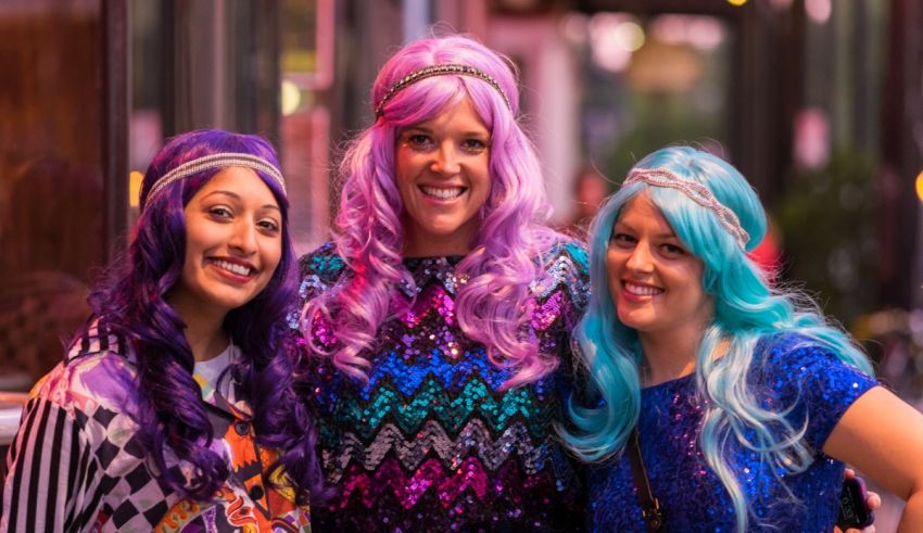 Three women with colorful wigs posing for a photo.