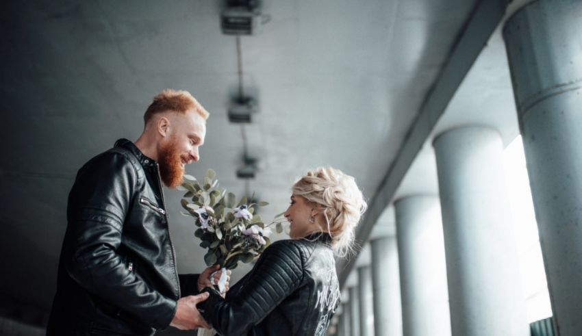 A man and woman in leather jackets are holding a bouquet of flowers.