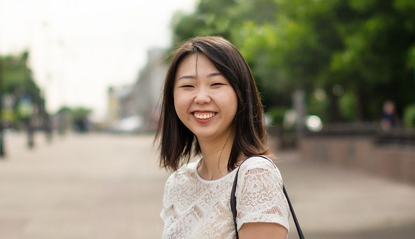 A young asian woman smiling in the street.