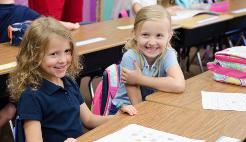 Two young girls sitting at desks in a classroom.