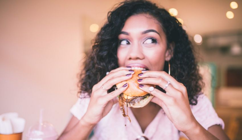A woman eating a hamburger in a restaurant.