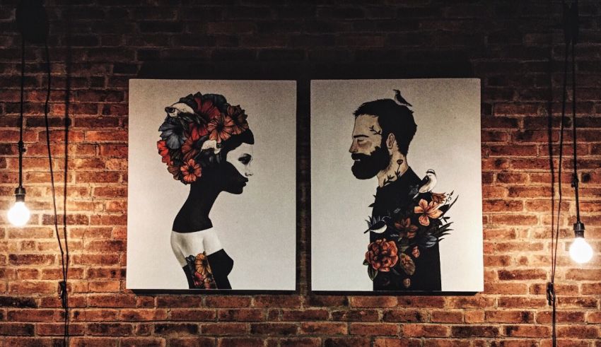 Two portraits of a man and a woman hanging on a brick wall.