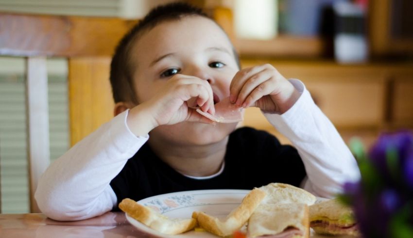 A young boy eating a sandwich at a table.