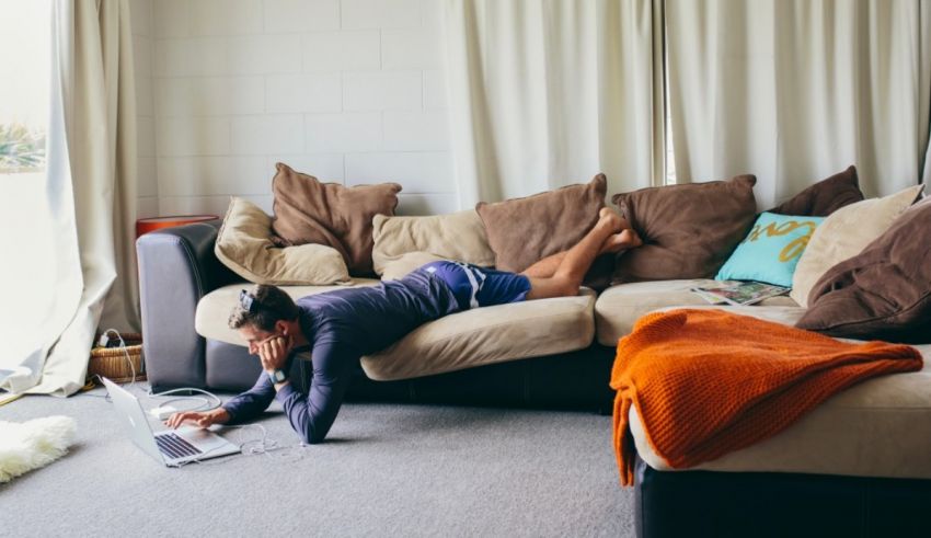 A man laying on a couch with a laptop on his lap.