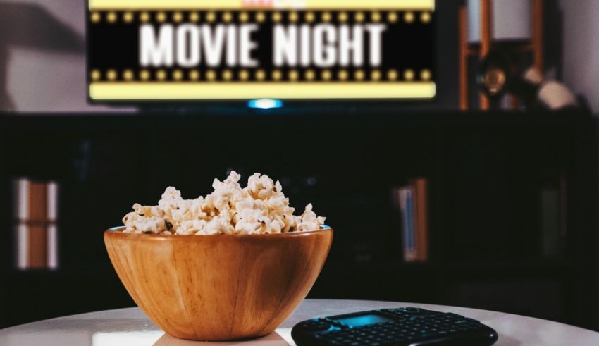 A bowl of popcorn on a table next to a tv.