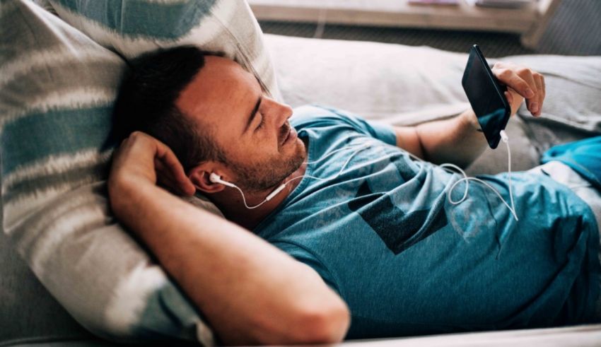 A man laying on a couch listening to music.
