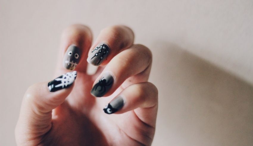 A person holding up a hand with black and white nail art.