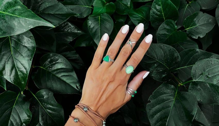 A woman's hand with green nails and a ring.