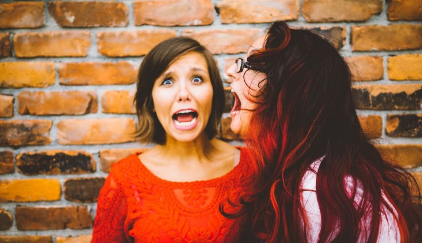 Two women laughing in front of a brick wall.