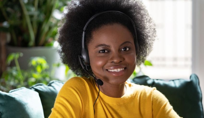 A young black woman wearing a headset while sitting on a couch.