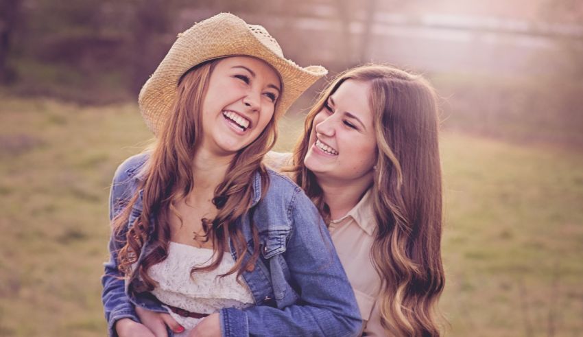 Two girls in cowboy hats laughing in a field.