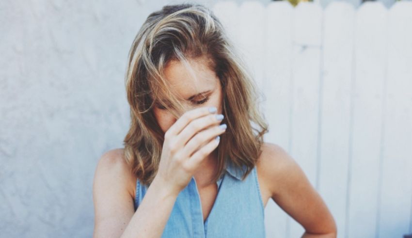 A woman covering her face with her hands.