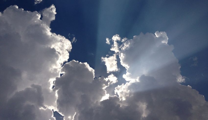 Rays of light shining through clouds in a blue sky.