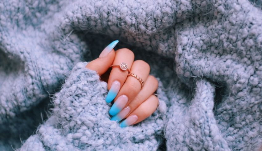 A woman's hand with blue nails and a blue ring.