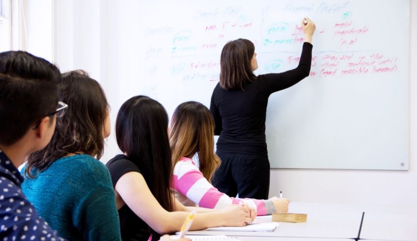 A woman is writing on a whiteboard in front of a group of people.