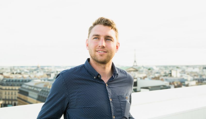 A man standing on a rooftop with a view of the eiffel tower.