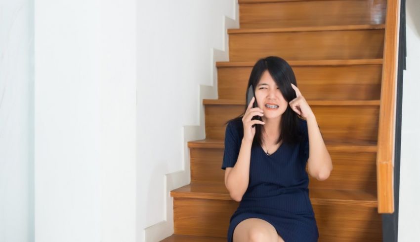 Asian woman talking on the phone while sitting on the stairs.