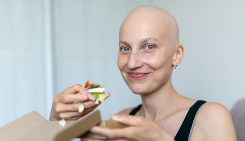 A woman with a bald head eating a sandwich.