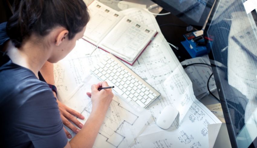 A woman is working on a blueprint at her desk.