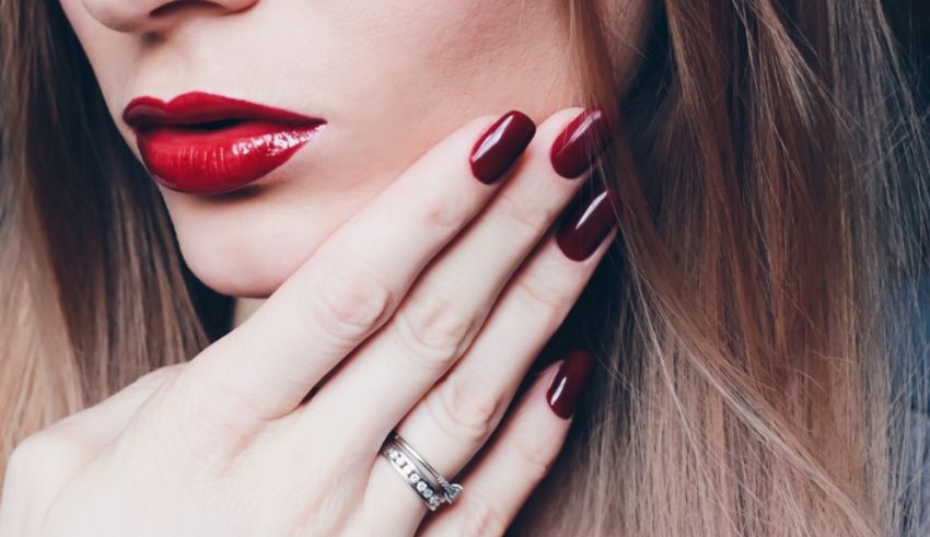 A woman with red nails and a ring on her hand.