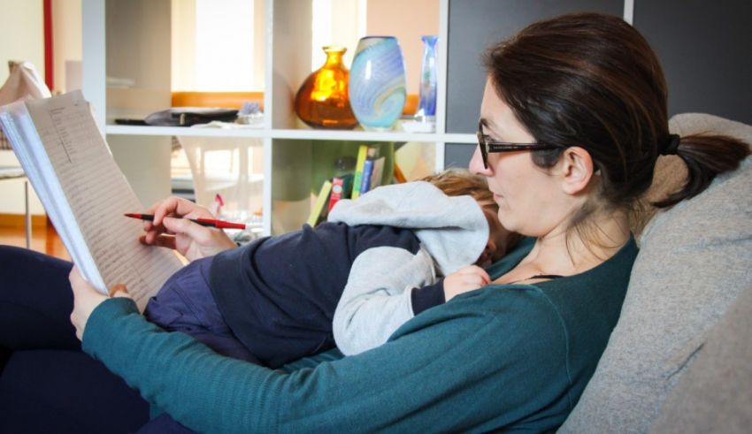 A woman is sitting on a couch reading a book to her child.