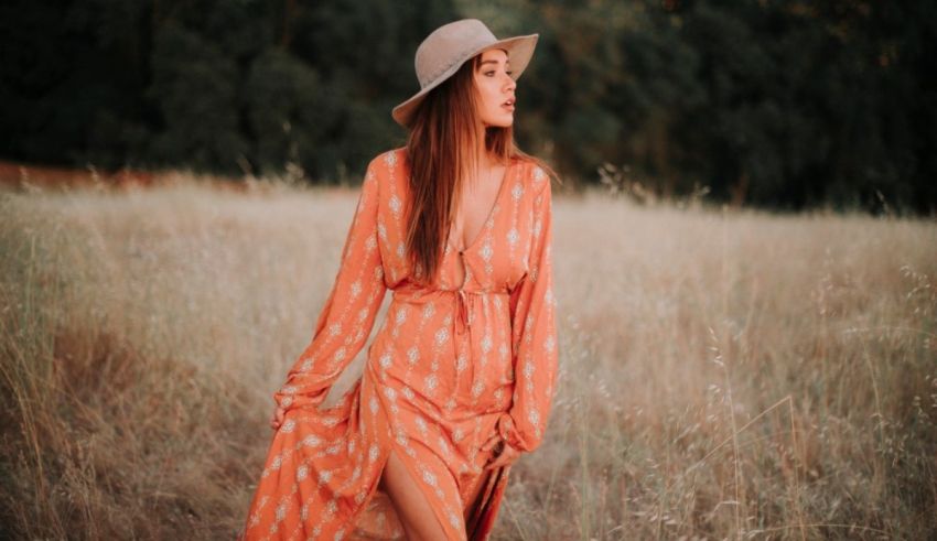 A woman wearing an orange dress and hat in a field.