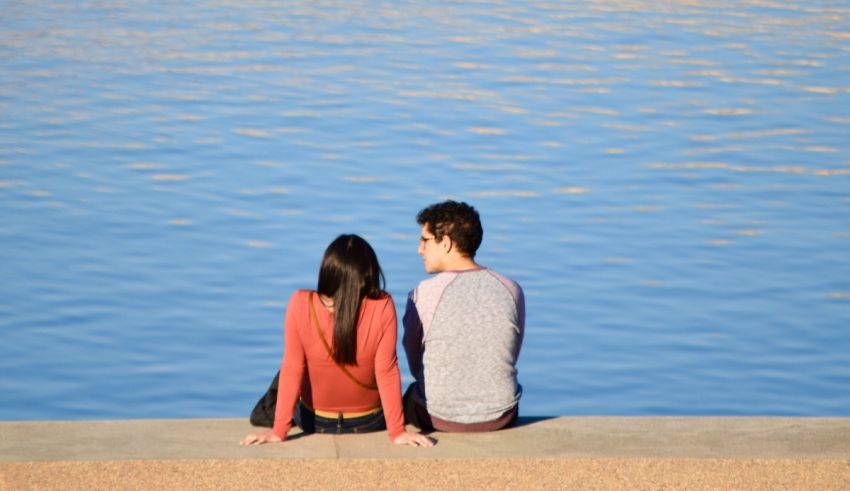 A couple sitting on a ledge looking at the water.