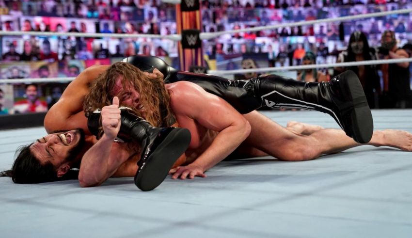 Two wrestlers are laying on the ground in a wrestling ring.