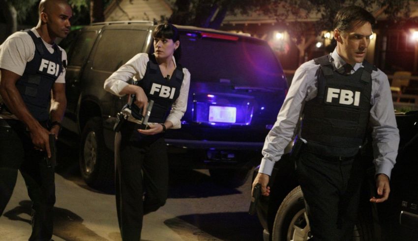 Three fbi agents standing next to a car.