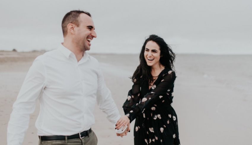 A couple walking on the beach holding hands.