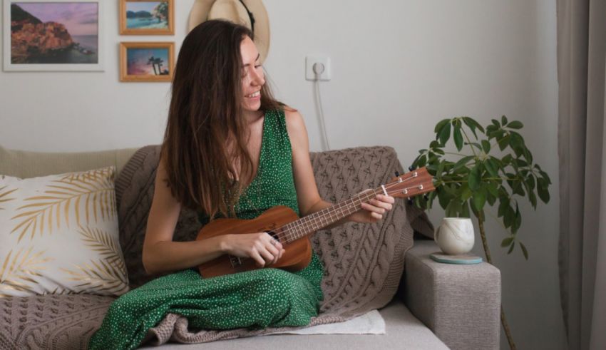 A woman is sitting on a couch playing an ukulele.