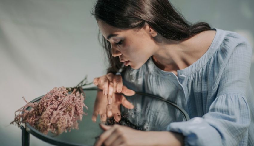 A woman is smelling flowers in a glass.