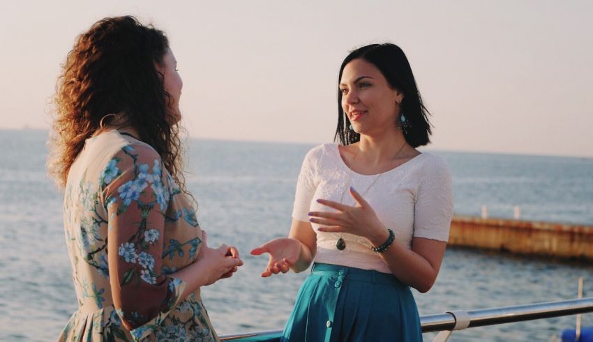 Two women talking on a deck near the water.