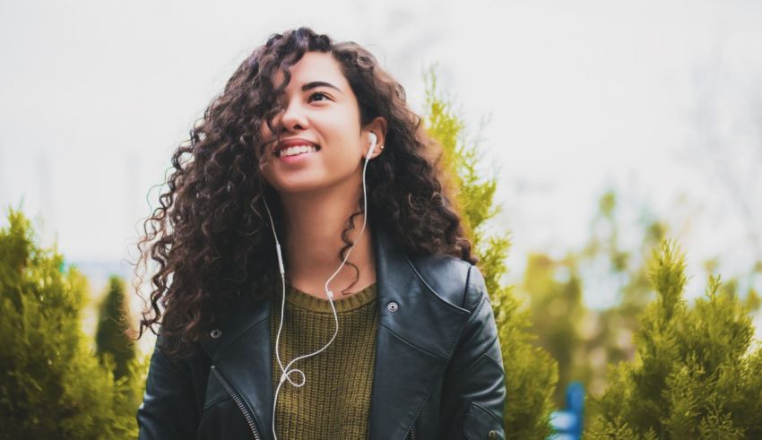 A young woman with curly hair listening to music.