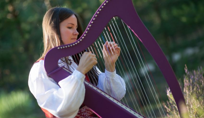 A woman is playing a purple harp in the woods.