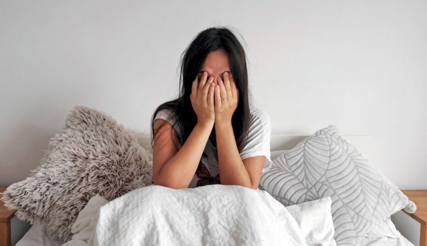 A woman covering her face in bed.