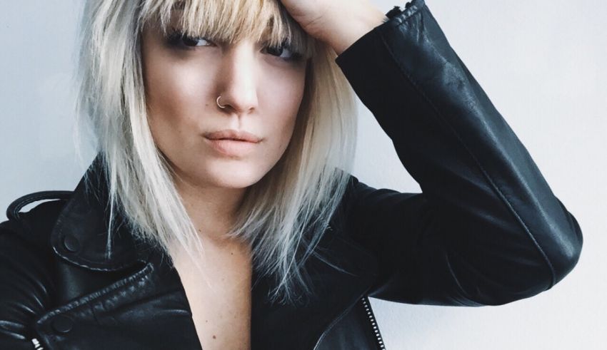 A blonde woman in a leather jacket posing for a photo.