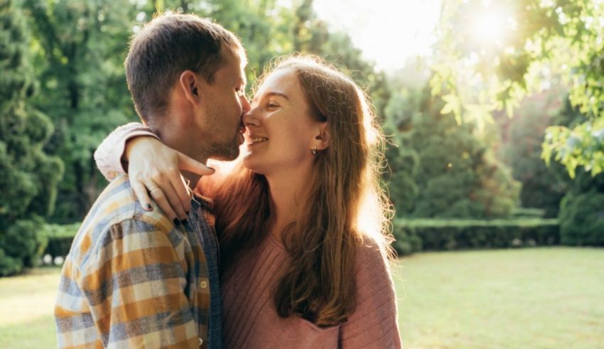 A young couple kissing in a park.