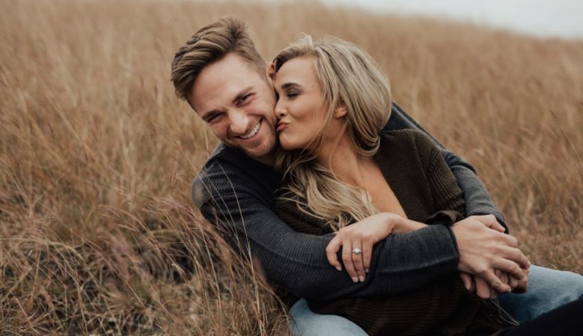 A couple embracing in a field during their engagement session.