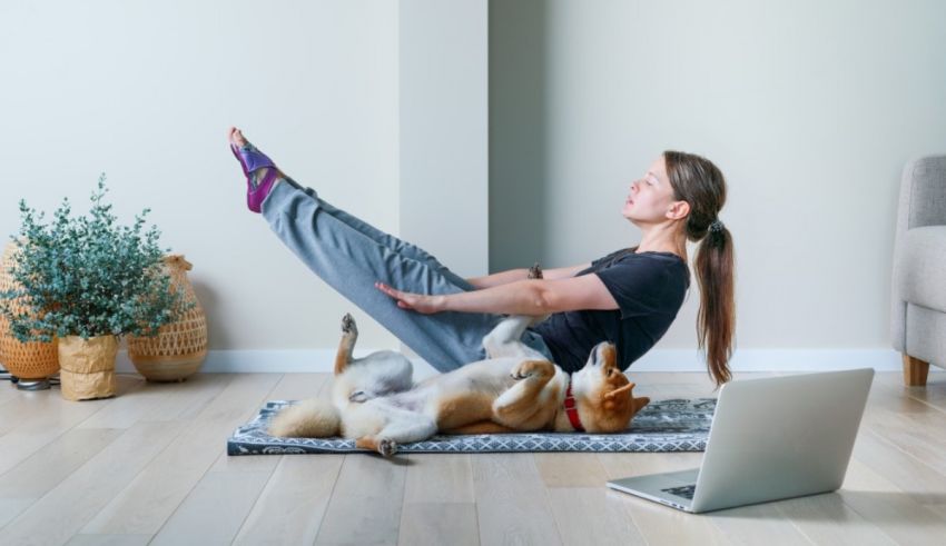 A woman is doing yoga with her dog on the floor.