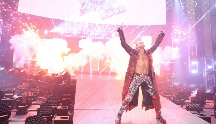 A wrestler standing on a stage with smoke coming out of his hands.