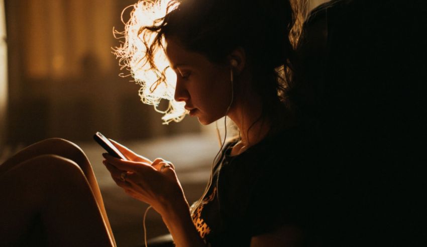 A woman sitting on a couch listening to music on her phone.