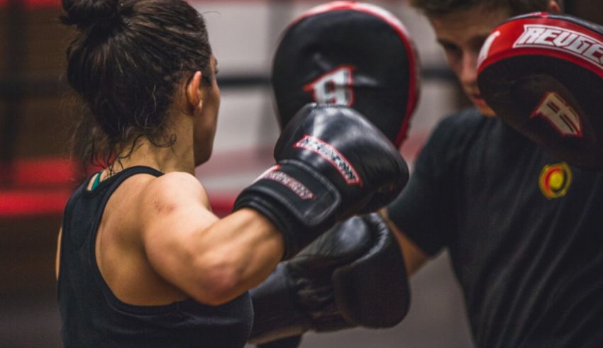 A woman and a man boxing in a gym.
