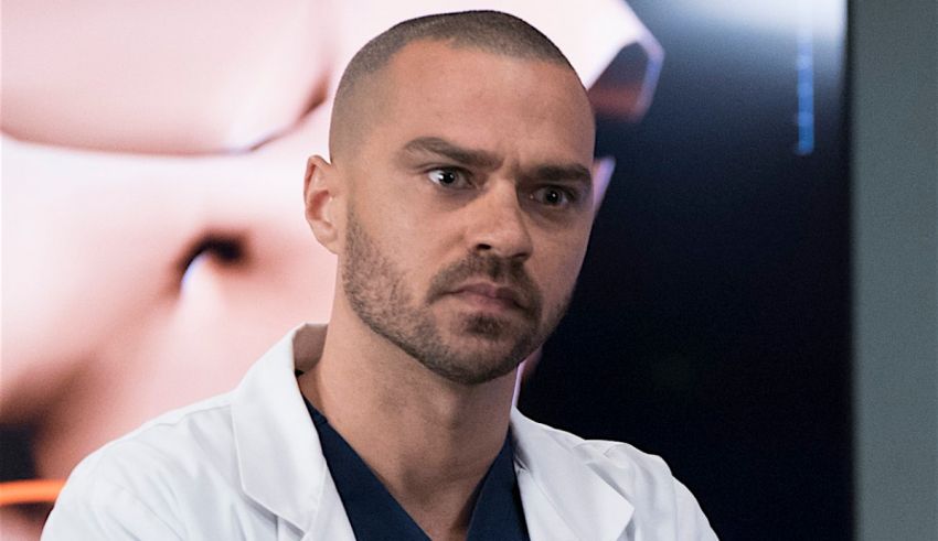 A man in a white lab coat is staring at a tv screen.