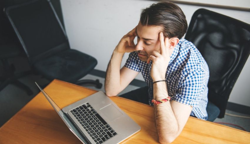 A man sitting at a desk with his hand on his head.