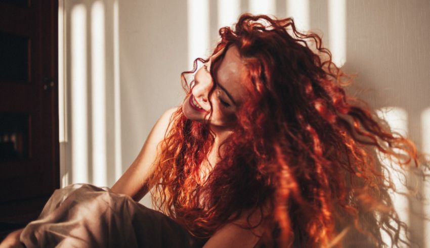 A woman with red curly hair sitting on the floor.